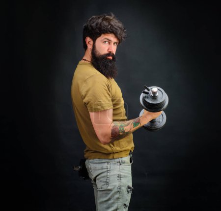 Photo for Strong bearded muscular sportsman training with dumbbell. Bodybuilder pumping muscle with dumbbell. Weightlifting. Muscular sportsman lifting dumbbell. Handsome athlete fitness model raising dumbbell - Royalty Free Image