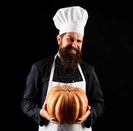 Smiling male chef in uniform with pumpkin. Bearded man in chef hat with squash. Organic food. Cook chef in white apron with pumpkin for culinary. Thanksgiving day. Autumn recipes. Seasonal vitamins