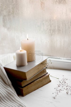 Photo for Old books and candles. Cozy postcard. White flowers. Romantic photo. A simple winter decoration on the windowsill. - Royalty Free Image