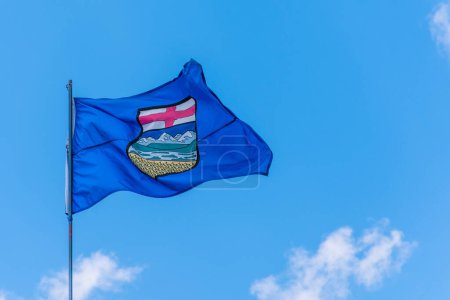 Canada Alberta provincial flag waving on a flagpole against blue sky background