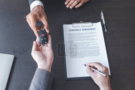 Konzept der Autoversicherung oder Vermietung, Verkäufer macht Deal mit Käufer und gibt ihm Schlüssel nach Unterzeichnung Verkaufsvertrag oder Mietvertrag.