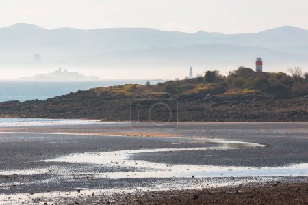 Photo for Moody, misty view at low tide from Silversands Beach in Aberdour, Fife, UK across the Firth of Forth to Edinburgh, and the Pentland Hills in Scotland. - Royalty Free Image