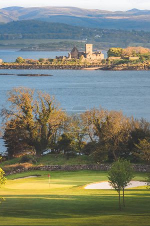 Photo for Scenic view of coastal golf hole and green and the Firth of Forth with the histoic Inchcolm Abbey and the Pentland Hills from Fife, Scotland - Royalty Free Image