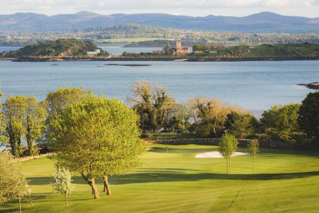 Photo for Scenic view of coastal golf hole and green and the Firth of Forth with the histoic Inchcolm Abbey and the Pentland Hills from Fife, Scotland - Royalty Free Image