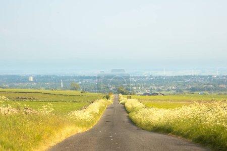 Photo for An empty country road straight ahead through rural rolling countryside landscape of Lomond Hills Regional Park towards Glenrothes, Fife, Scotland, UK on a sunny summer day. - Royalty Free Image