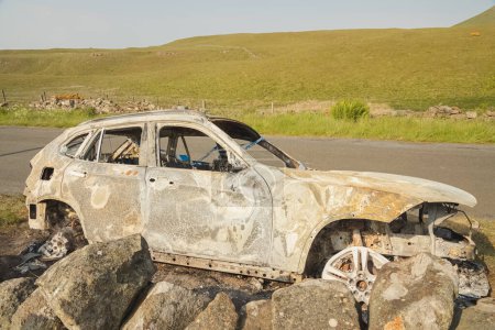 Téléchargez les photos : Scène d'un accident de voiture avec une cassette de police sur une épave de voiture brûlée sur une route de campagne dans le parc régional Lomond Hills, Fife, Écosse, Royaume-Uni. - en image libre de droit