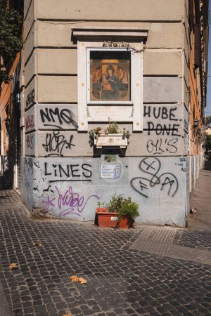 Photo for Rome, Italy - August 27, 2023: Urban street graffiti and spray paint on an old residential building juxtaposes an historic religious art piece of a Madonna and Child fresco in the trendy neighbourhood of Trastevere. - Royalty Free Image