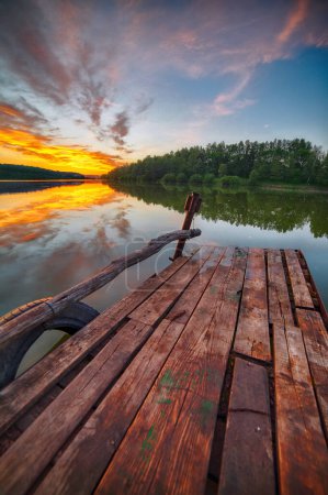 Photo for Amazing Wooden dock, pier, on a lake in the evening. Dramatic sunset - Royalty Free Image