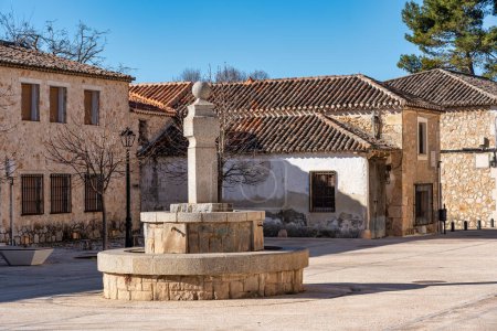 Stone fountain in a square with old buildings of the medieval village of Nuevo Baztan, Madrid