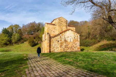 Foto de Mujer caminando junto a una antigua iglesia románica situada en el norte de España, Asturias - Imagen libre de derechos