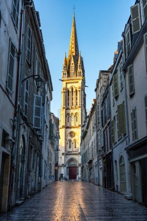Photo for Narrow alley with picturesque streets and old church in the background illuminated by the sun, Pau, France - Royalty Free Image