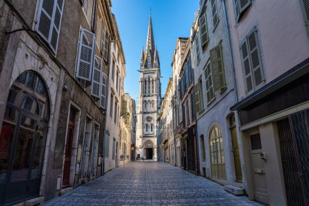 Photo for Narrow alley with picturesque streets and old church in the background illuminated by the sun, Pau, France - Royalty Free Image