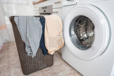 Kleider, die an einem Korb hängen, bereit, sie in die automatische Waschmaschine zu legen