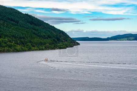 Photo for Boat sailing on the huge Loch Ness in central Scotland, surrounded by mountains - Royalty Free Image