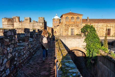 Foto de Mujer turista paseando por la muralla de la ciudad medieval de Cáceres - Imagen libre de derechos