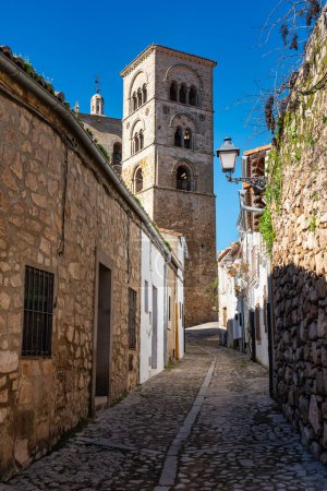 Enge Gasse, die zu einem mittelalterlichen Kirchturm in Trujillo, Spanien führt.