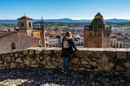 Tourist woman leaning over the medieval wall contemplating the city of Trujillo, Spain