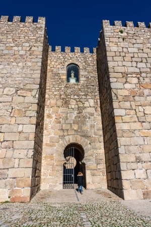 Touristin auf dem Weg durch das Eingangstor zur mittelalterlichen Burg von Trujillo, Extremadura