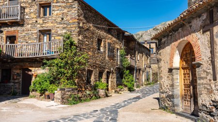Village church with stone houses around next to the mountain, Castilla la Mancha, Spain