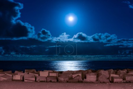 The moon rising above the clouds and reflecting its light on the sea on the coast of La Palma, Canary Islands