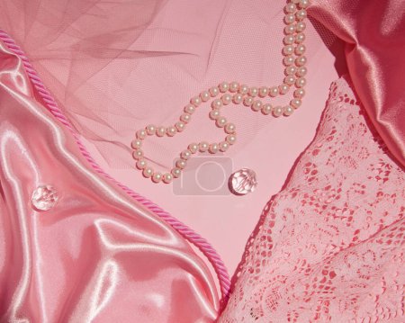 Photo for Combination of feminine fabrics, tulle, lace, beads, pastel pink creative background. - Royalty Free Image