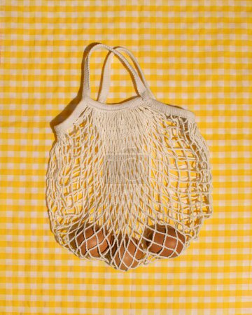 Eggs in a mesh grocery bag, Easter shopping, gingham pattern tablecloth, retro aesthetic.
