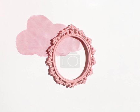 Pink cloud cut from silk fabric, oval picture frame over, creative background.