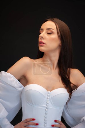 Beautiful young woman in white wedding dress and makeup posing