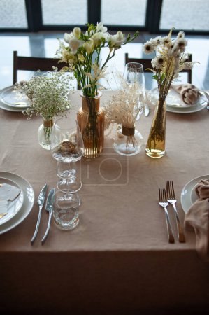 Beautiful table setting with flowers and cutlery on wooden table at wedding or dinner
