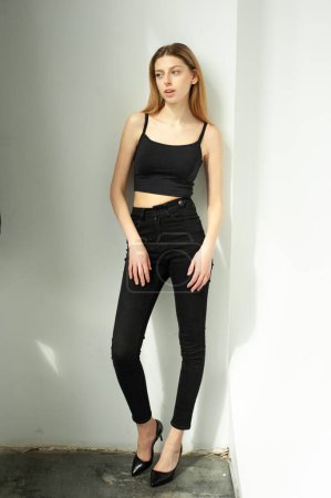 Beautiful young girl in black pants posing in studio on white background