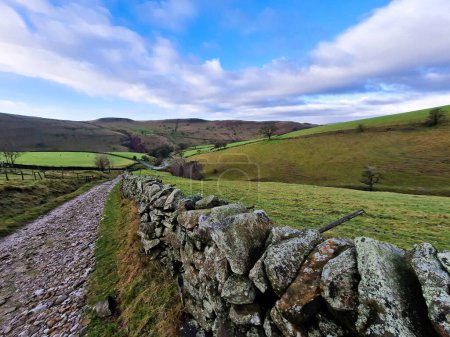 A stunning panoramic view of the Peak District's undulating hills and weaving pathways, captured on a clear day, showcasing the natural beauty of England's countryside.