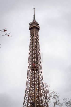 Photo for Autumn branches on the Eiffel Tower in Paris with its rising red elevator - France - Royalty Free Image