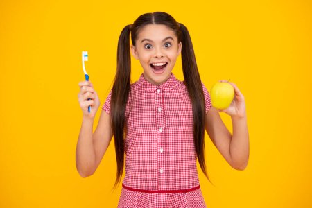 Oral hygiene, dental. Teenage girl brushing her teeth. Teen holds a toothbrush in hand brushing her teeth morning routine dental hygiene, teeth care. Apple vitamins for healthy teeth