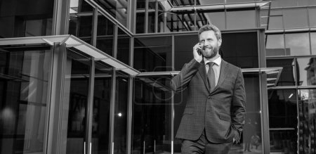 Lächelnder erfolgreicher bärtiger Geschäftsmann im formellen Anzug spricht auf Smartphone, Gespräch.