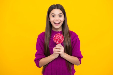Photo for Funny child with lollipop over yellow isolated background. Sweet childhood life. Teen girl with yummy caramel lollipop, candy shop. Teenager with sweet sucker - Royalty Free Image