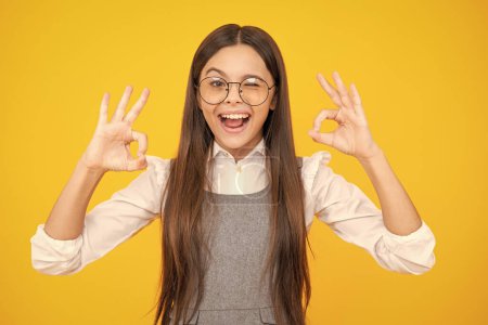 Foto de Niña muestran dedos ok símbolo lenguaje de señas aislado sobre fondo amarillo. Cara de adolescente graciosa. Cara excitada. Expresión asombrada, alegre y alegre - Imagen libre de derechos