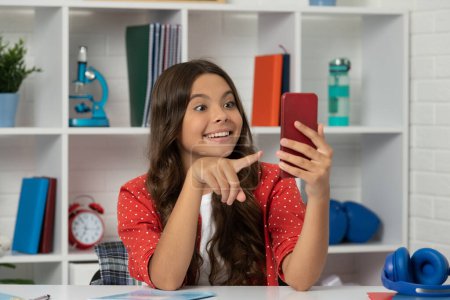 Foto de Amazed teen girl making video pointing finger on selfie using mobile phone, content maker. - Imagen libre de derechos