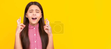 Photo for Glad teenager girl crosses fingers, closes eyes with pleasure, anticipate hearing good news. Child face, horizontal poster, teenager girl isolated portrait, banner with copy space - Royalty Free Image