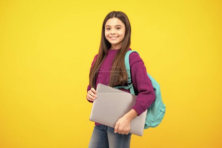 Téléchargez les photos : Schoolchild, teenage student girl with laptop on yellow isolated studio background. Children school and education concept - en image libre de droit