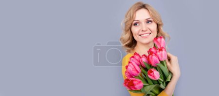 mujer positiva con tulipanes sobre fondo gris. Retrato de cara aislada mujer, pancarta con espacio de copia simulada