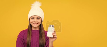 Photo for Smiling child in winter hat with pill jar. food supplement. teen girl with natural pill products. Horizontal poster of isolated child face, banner header, copy space - Royalty Free Image