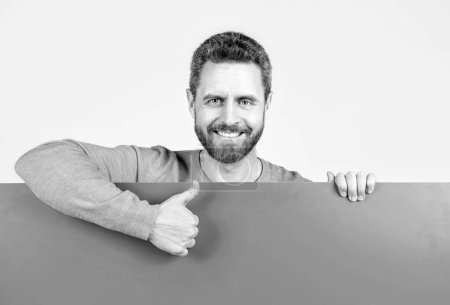 Photo for Happy mature bearded man behind blank pink paper banner with copy space for job offer show thumb up, proposition. - Royalty Free Image