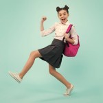 Amazed teenager. School girl in school uniform with backpack. Teenage girl student on blue isolated background. Learning knowledge and kids education concept. Jump and run. Excited teen girl