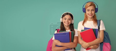 Téléchargez les photos : Mother and daughter child banner, copy space, isolated background. mother and daughter in earphones hold notebook and backpack ready to study, ebook - en image libre de droit
