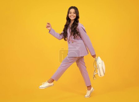 Téléchargez les photos : Back to school. Fashion teenage school girl ready to learn. School children on yellow isolated background. Run and jump. Happy face, positive and smiling emotions of teenager girl - en image libre de droit