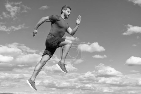 Téléchargez les photos : Homme énergique athlète sprinter avec corps musclé courir en vêtements de sport en plein air sur fond de ciel, la motivation. - en image libre de droit