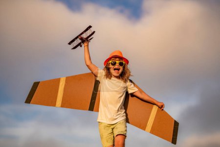 Photo for Child in the village with plane in his hands. Happy kid playing with toy paper wings outdoors in summer field. Travel and kids vacation concept. Imagination and freedom - Royalty Free Image