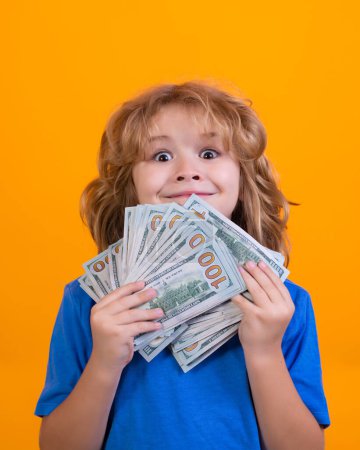 Téléchargez les photos : Enfant montrant des billets d'argent en dollars, rêvant de riches dans un studio isolé - en image libre de droit