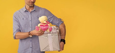 cropped mature man hold box and toy on yellow background, copy space, anniversary .