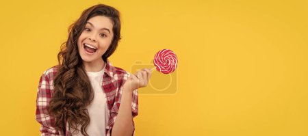 Photo for Lollipop child. hipster kid with long curly hair hold lollypop. sugar candy on stick. caramel candy shop. sweet childhood life. teen dental care. sweet tooth. yummy. funny girl hold lollipop. - Royalty Free Image
